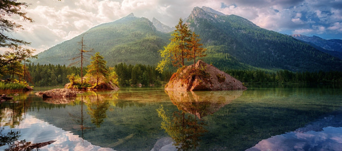 See mit Bergen im Hintergrund, die sich im Wasser spiegeln