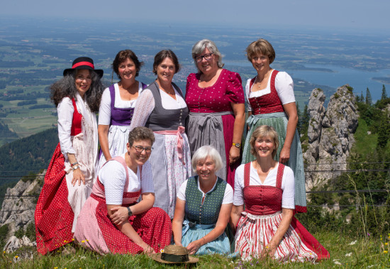 Eine Gruppe mit 8 Damen in Trachten auf einer Bergwiese, im Hintergrund der Chiemsee.